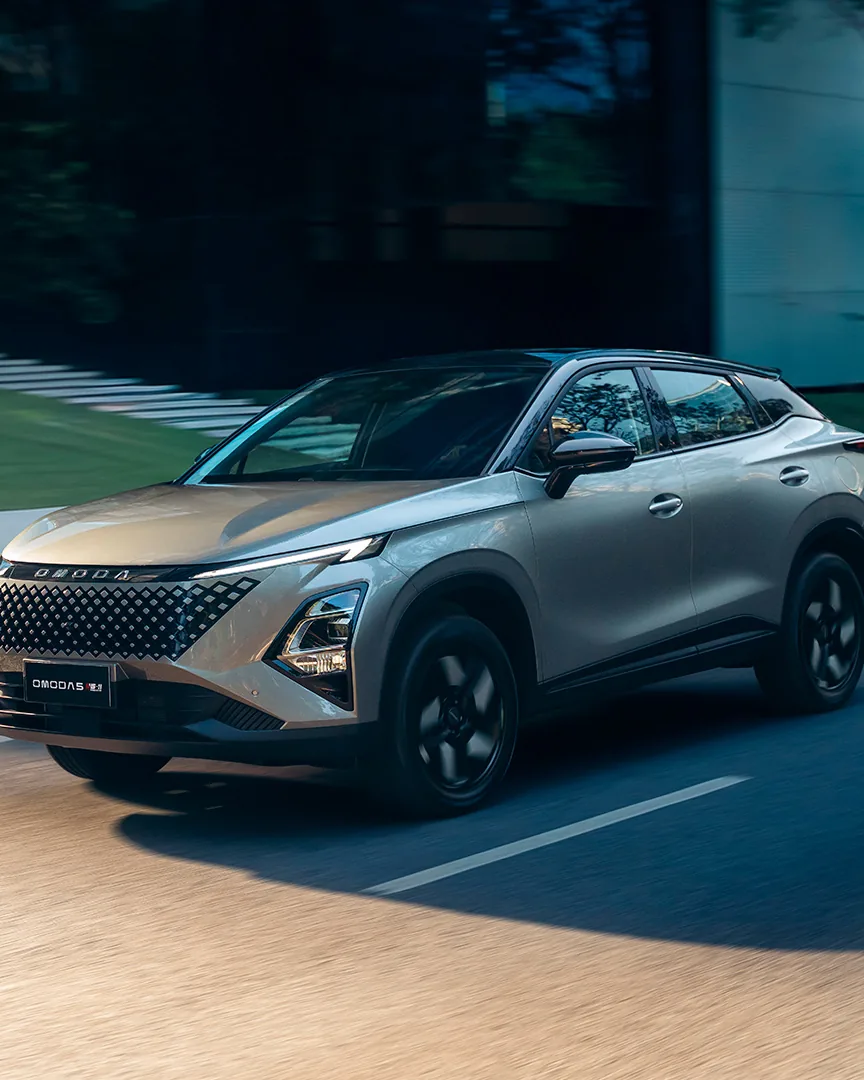 OMODA 5 SHS-H, SUV híbrido na cor champanhe, em movimento numa via arborizada