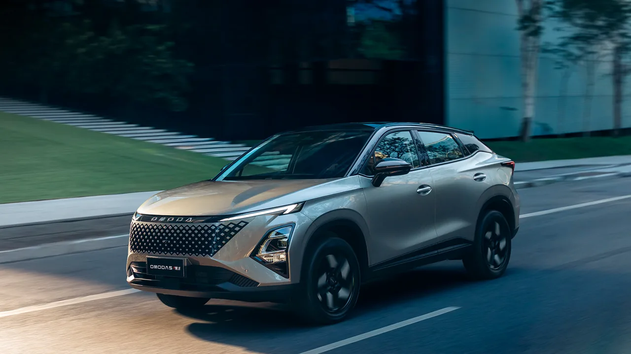 OMODA 5 SHS-H, SUV híbrido na cor champanhe, em movimento numa via arborizada
