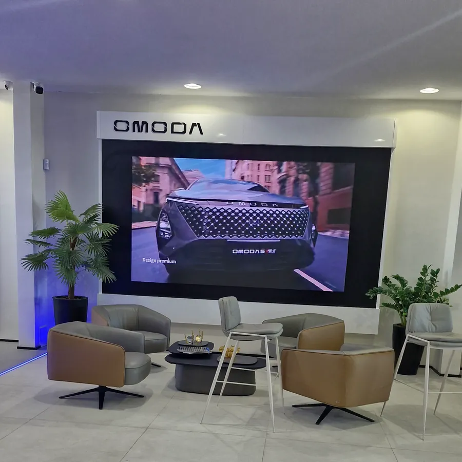 Espaço OMODA do showroom, com telão de vídeo e poltronas para atendimento