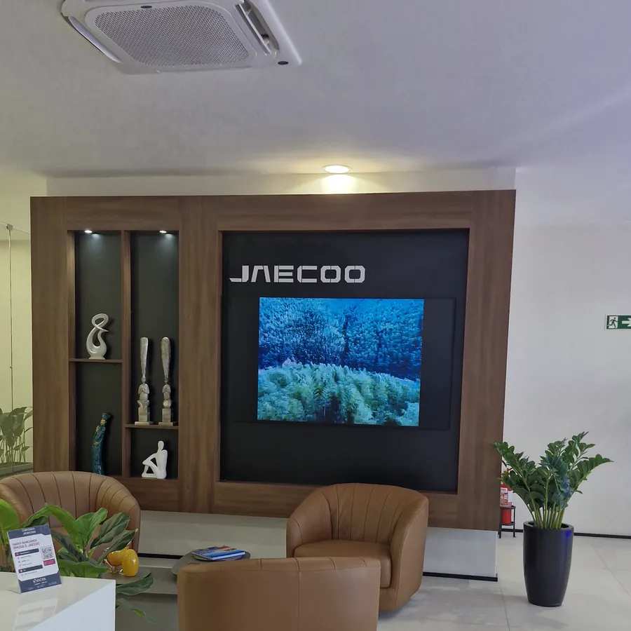 Lounge de espera da Omoda Jaecoo Socel, com poltronas e o painel JAECOO iluminado ao fundo