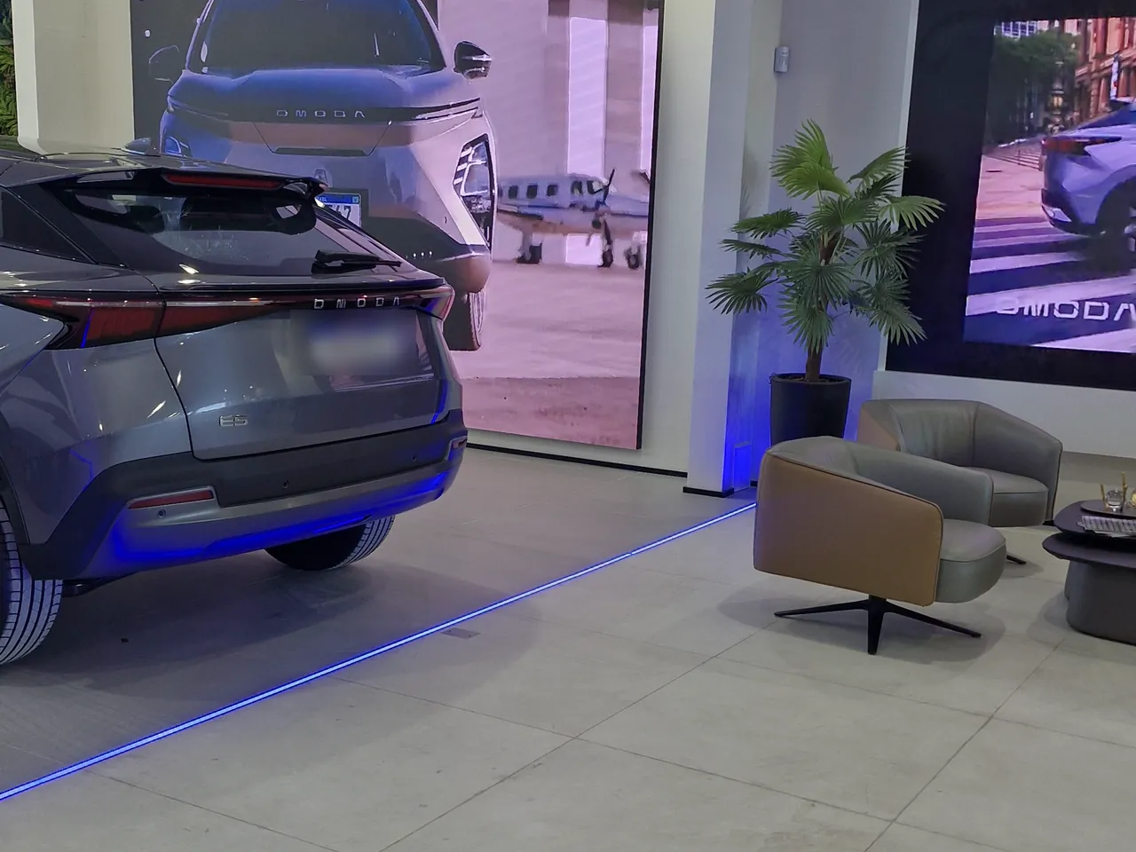 Showroom da Omoda Jaecoo Socel, com o OMODA E5 em exposição diante do painel de vídeo